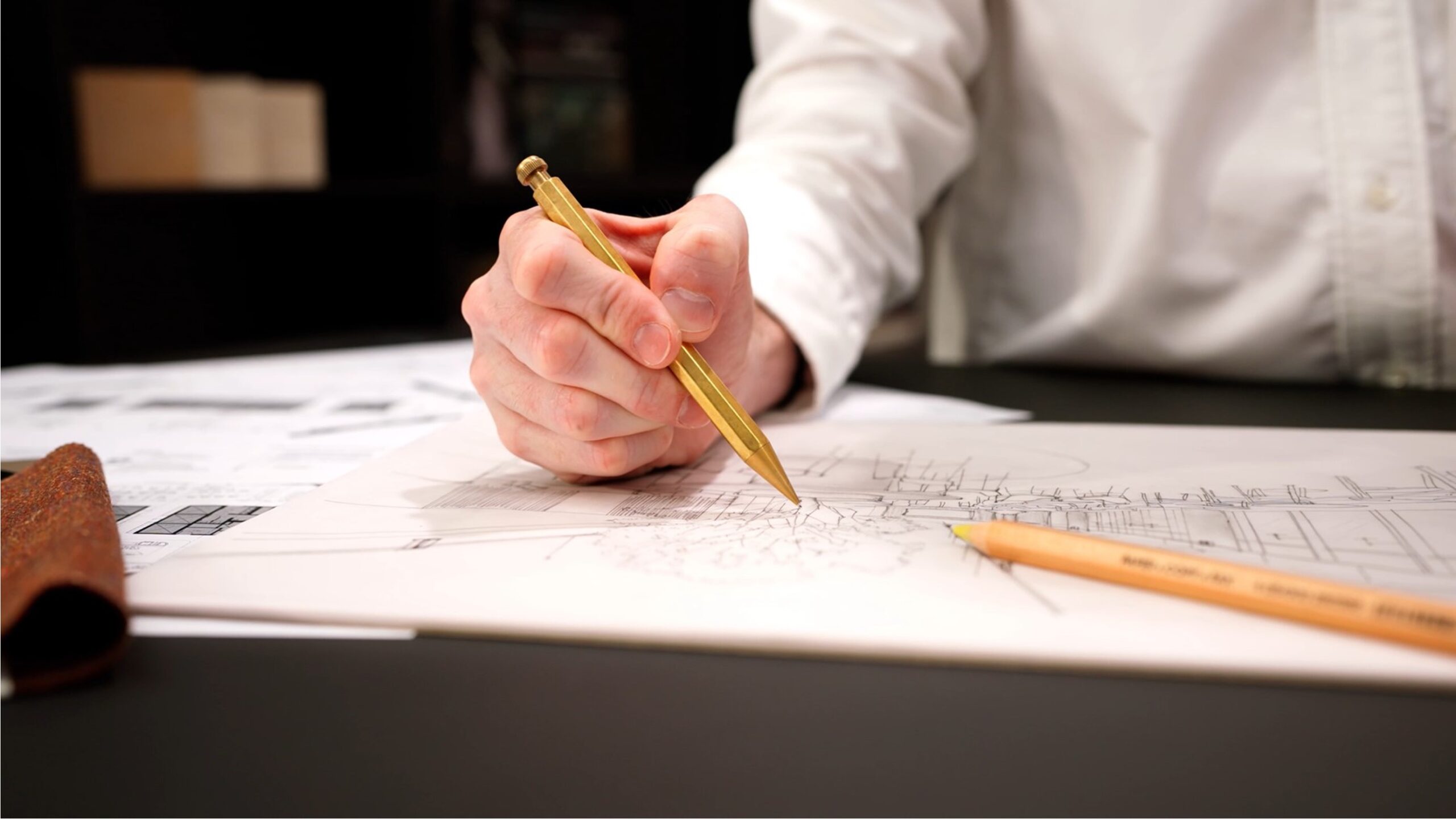 person sketching on top of building plans